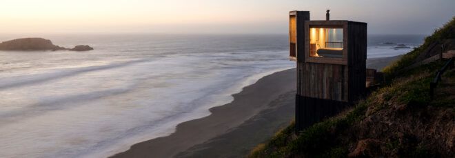 light and dark wood cabin overlooking the ocean at dusk