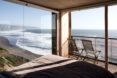 gray bed facing glass walls overlooking ocean