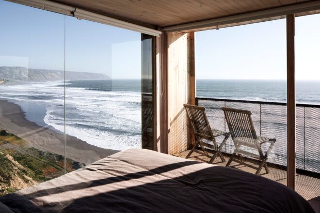 gray bed facing glass walls overlooking ocean