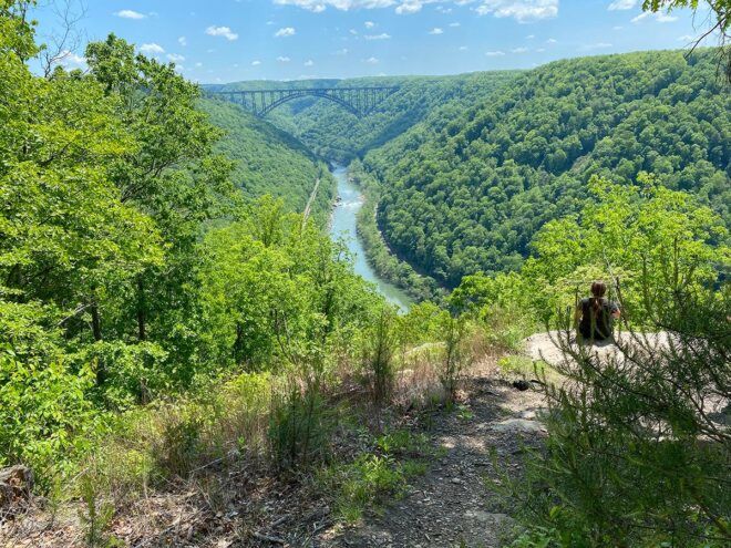 person sitting on rock overlooking New River Gorge