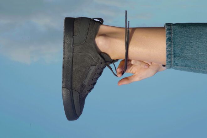 person tying black sneaker