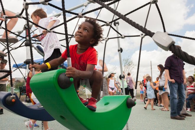child playing on green riding toy at a park