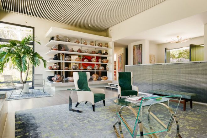 large living room with white and green chairs and shelves of pottery