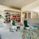 large living room with white and green chairs and shelves of pottery