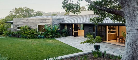 black, white and wood home with large patio and grassy yard