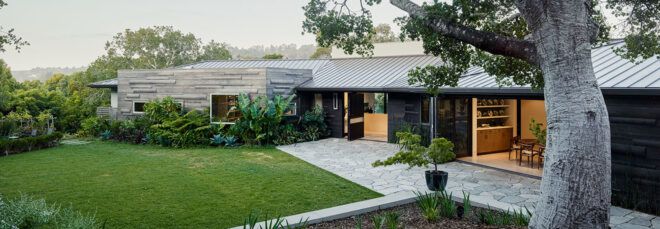 black, white and wood home with large patio and grassy yard
