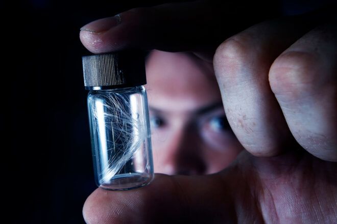 person holding thin fibers in glass vial