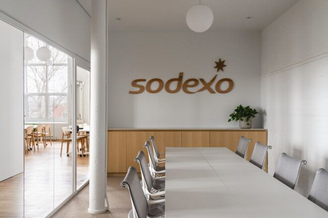 meeting room with wood sign on wall that reads "Sodexo"