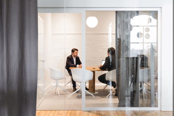 people sitting at desk in meeting room with glass walls