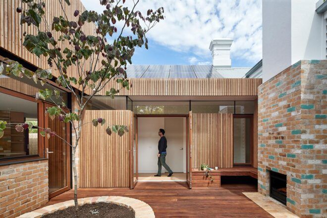 timber and brick home with timber doors open to a patio