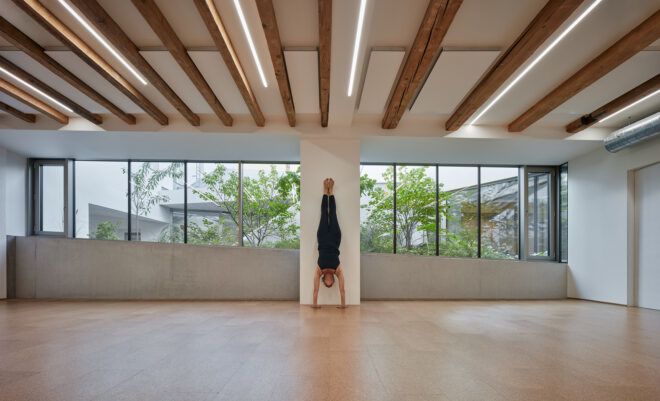 person doing handstand in large white room with wood beam ceiling