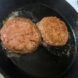 two sizzling Beyond burgers on cast iron skillet