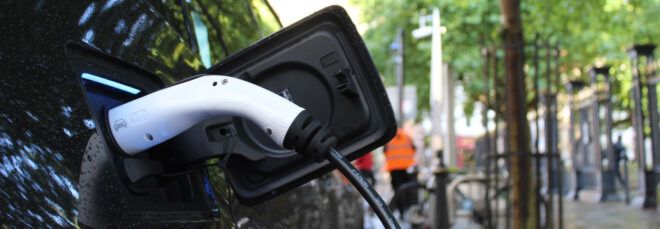 black electric vehicle plugged into charger