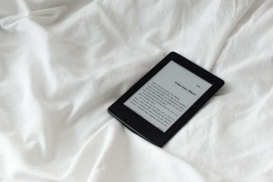 e-reader on white bedsheets