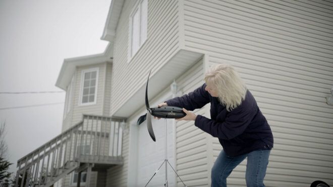 person assembling portable wind turbine outside house