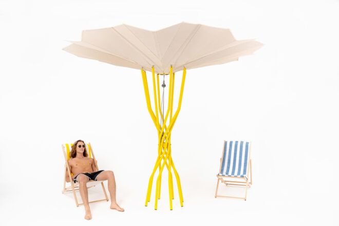 person sitting in beach chair underneath yellow and tan solar-powered beach umbrella