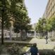 A green courtyard with trees and grass. People loiter in the area.