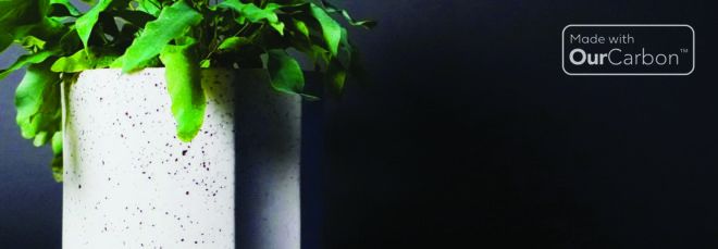 To the left, a green plant inside a black and white speckled pot. To the right, text reading "Made with OurCarbon."
