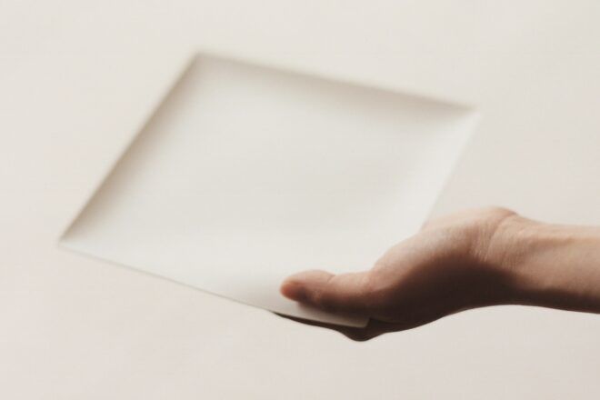 A hand holding a square plate.