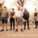 A group of five people standing in an outdoor basketball court.