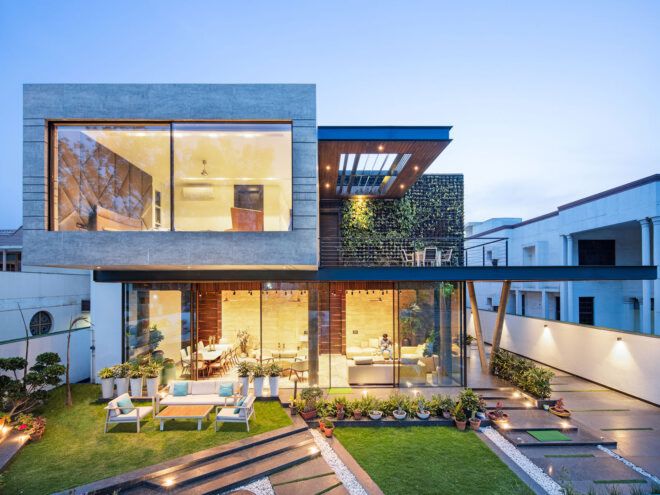 concrete cantilevered house covered in plants at dusk