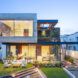 concrete cantilevered house covered in plants at dusk