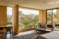 bed facing wall of glass with forest views