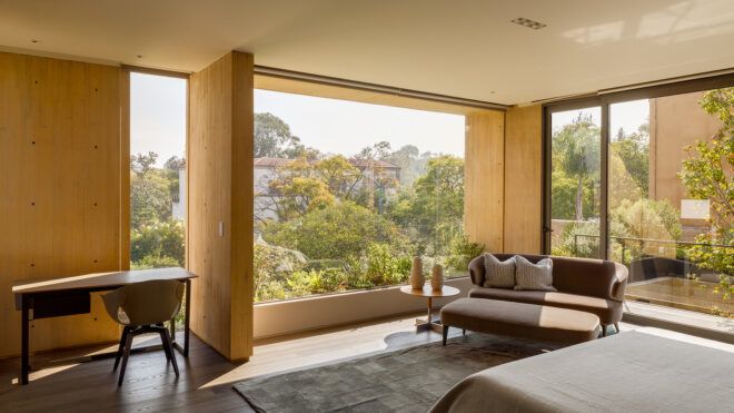 bed facing wall of glass with forest views