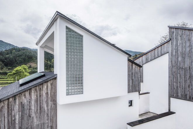 white and wood home with steep sloped roofs