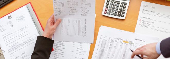 A table with reports and two hands interacting with them.