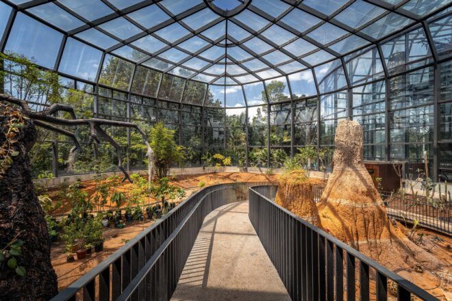 A greenhouse building with walking trails, greenery and trees.