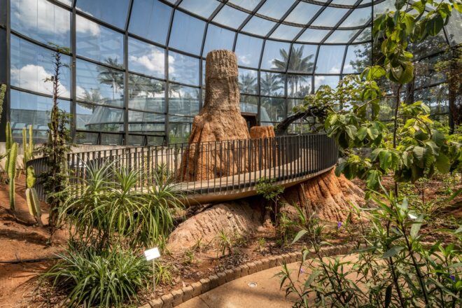 A greenhouse building with walking trails, greenery and trees.