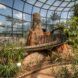 A greenhouse building with walking trails, greenery and trees.