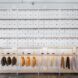 A wall of white cabinets and drawers about a row of clothing racks.