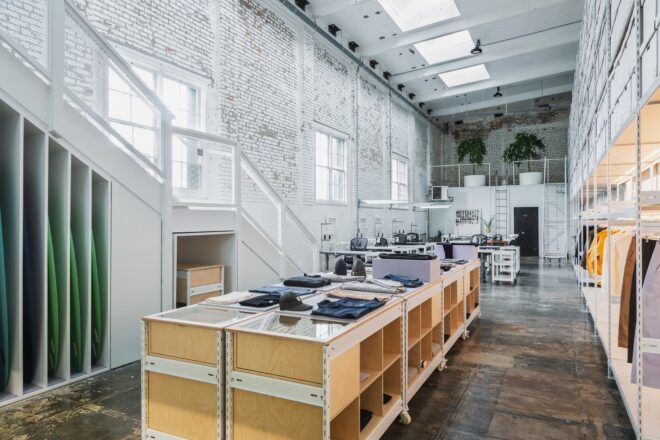 White walls lining a clothing facility with wood workbenches.