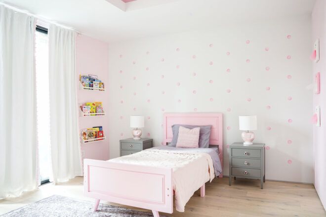 A child's room featuring white and pink walls and a pink bed.