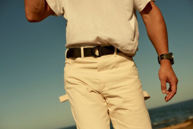person wearing white outfit and black recycled plastic utility belt