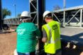 person in Habitat for Humanity shirt and person in PERI Group shirt working together on construction site