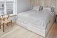 fluffy white bed in bright white room with one wood accent wall
