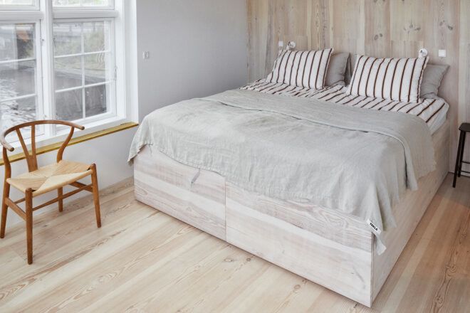 fluffy white bed in bright white room with one wood accent wall