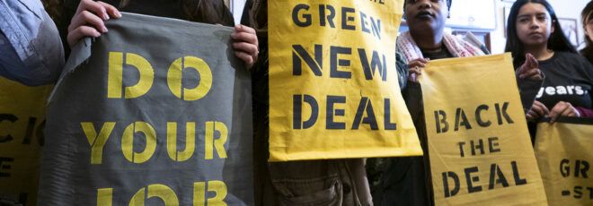 A line of protestors holding signs that say "do your job," "green new deal," and "back the deal."