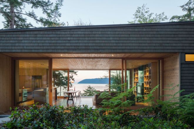 wood home with glass walls revealing views of Pacific Ocean