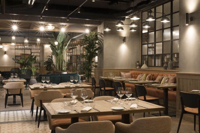 A neutral-toned restuarant space with several tables and chairs.