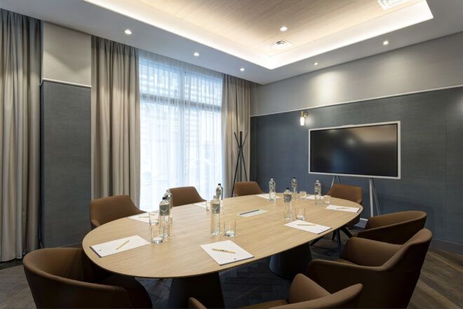 A meeting room with several chairs around an oval-shaped wood table.