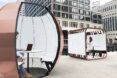 rendering of people working on computers inside gold and white pods
