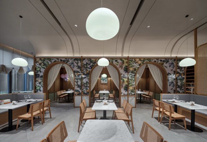 A dining room with several chairs and tables, with patterned wallpaper on the walls.