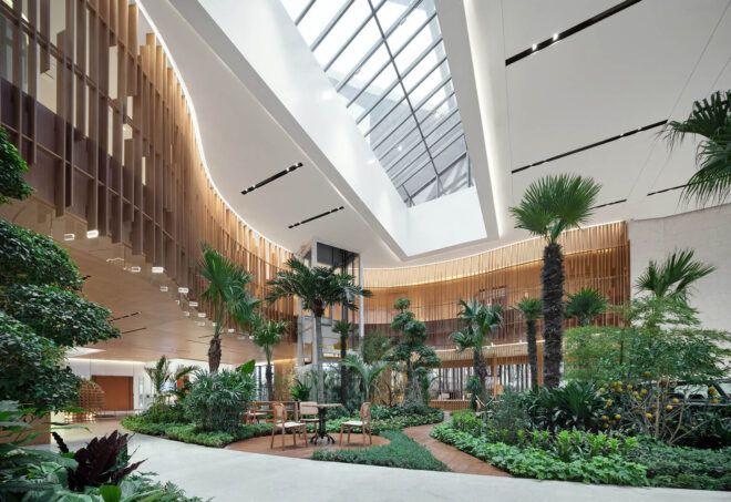 A plant-filled lobby with natural wood accents around the ceiling.
