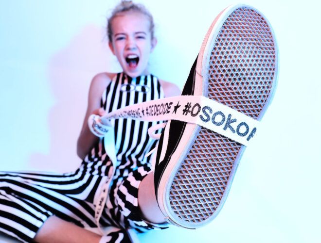 kid with ribbon that reads "Osokoa" wrapped around the kid's shoe