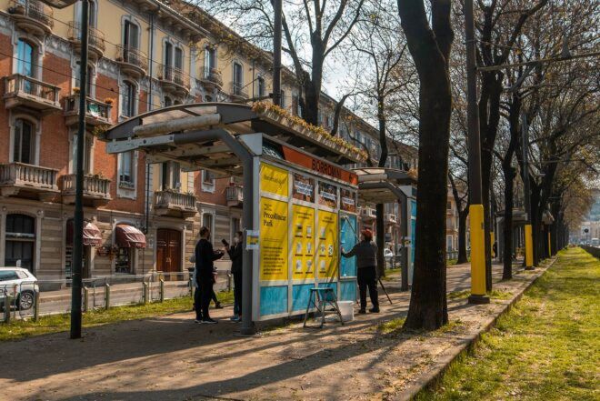 people plastering posters on bus stop