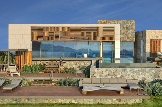 gray furniture on wood patio connected to white and wood villa
